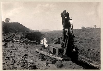 Ansicht von Arbeitern, die den Panamakanal graben, mit Eisenbahnschienen durch einen Graben und einer Art Grabmaschine im Vordergrund, 1912 oder 1913 von Byron Company